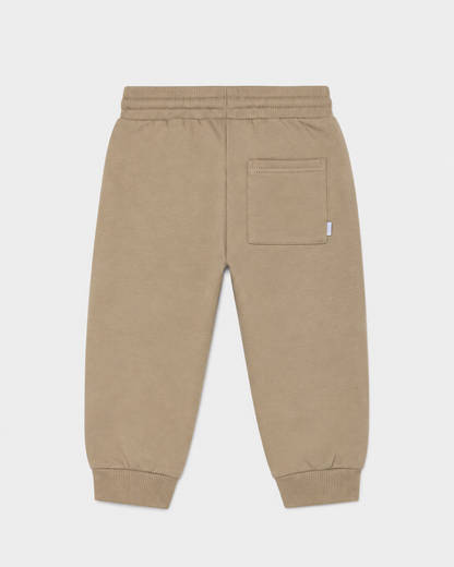 Hazelnut brown baby jogger pants with elastic waistband, ribbed cuffs, and a single right-side back pocket. Available in sizes 0-3M, 3-6M, 6-12M.