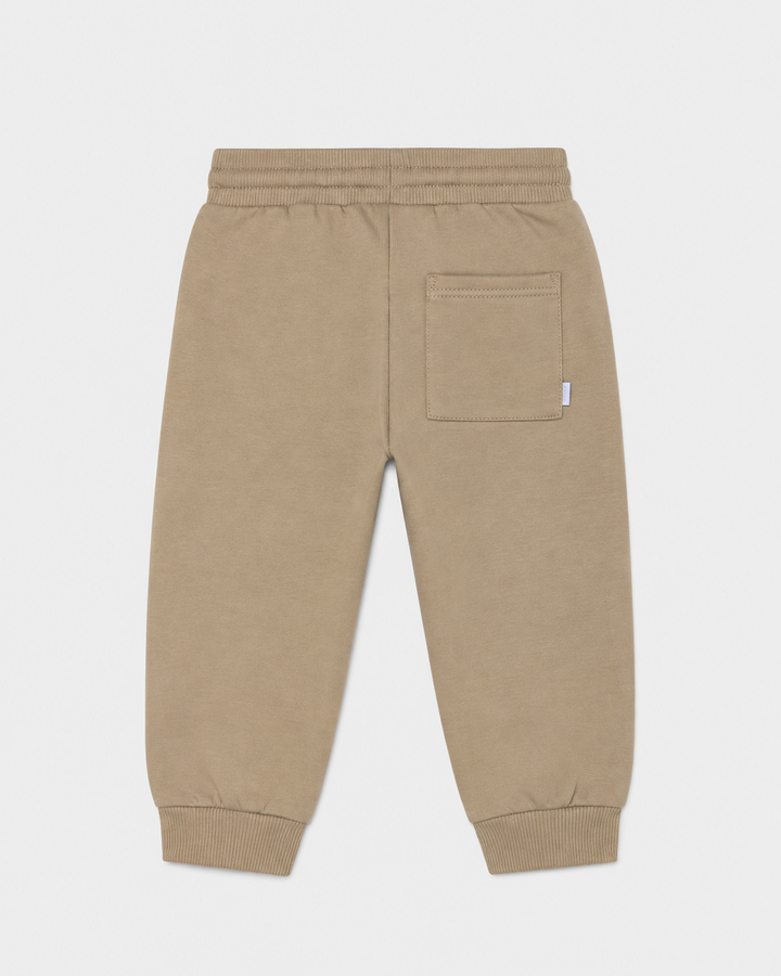 Hazelnut brown baby jogger pants with elastic waistband, ribbed cuffs, and a single right-side back pocket. Available in sizes 0-3M, 3-6M, 6-12M.