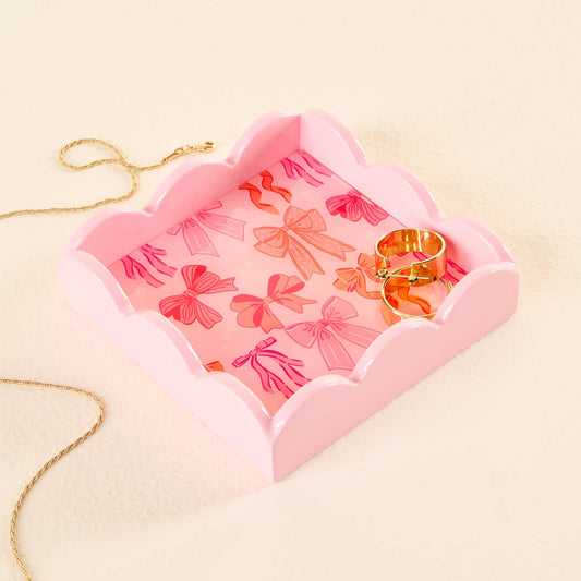 The Scallop Trinket Tray-Blushing Bows has a pink bow pattern. Available sizes: small, medium, large.