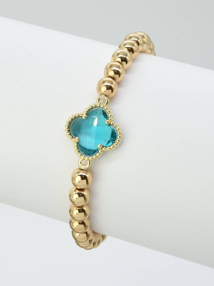 Gold beaded bracelet with central crystal clover charm. Available in sizes S, M, and L.