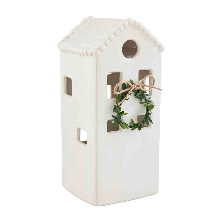 Tall white stoneware lantern with a milk glazed finish, square windows, and a small greenery wreath tied with twine.