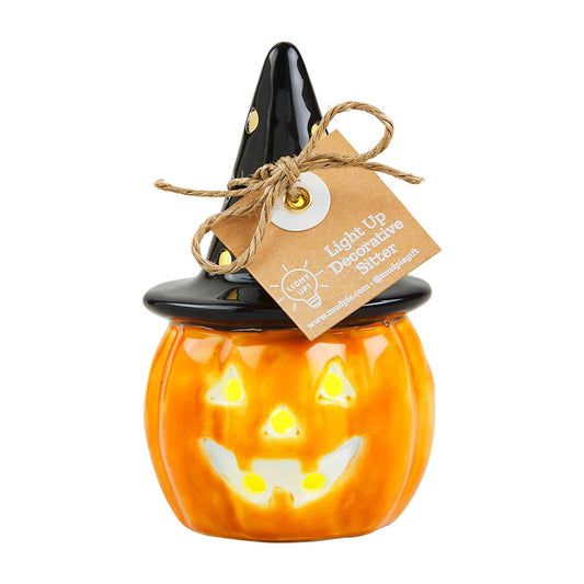 The Light-Up Witch Jack-O-Lantern Sitter is a ceramic pumpkin with a carved smiling face and a black witch hat with a twine bow, featuring LED lights for an inviting glow. Available in one size.
