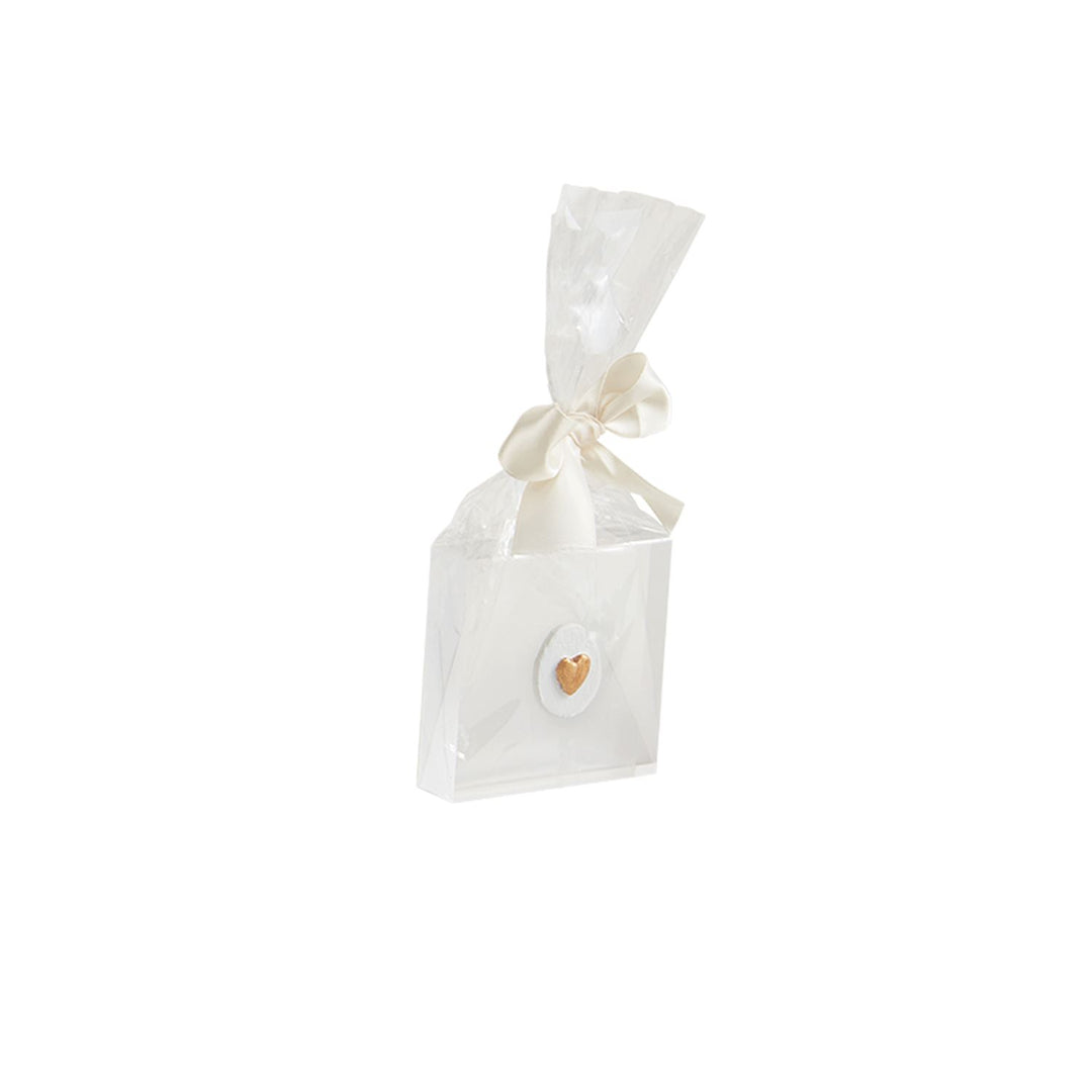 White gift bag with a shiny finish, tied with a white ribbon. Features "Mini Acrylic Icon Plaques" and a circular detail with a gold heart on the front. Sizes available: One size.
