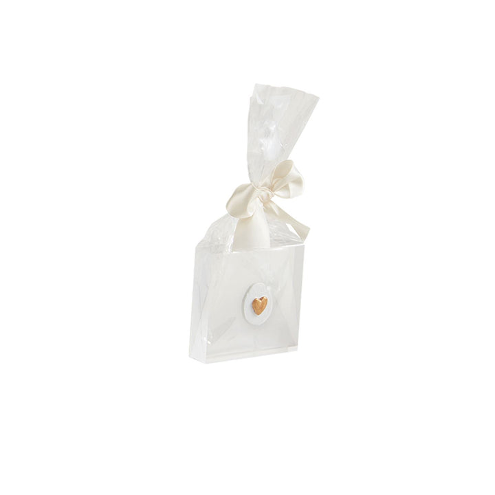 White gift bag with a shiny finish, tied with a white ribbon. Features "Mini Acrylic Icon Plaques" and a circular detail with a gold heart on the front. Sizes available: One size.