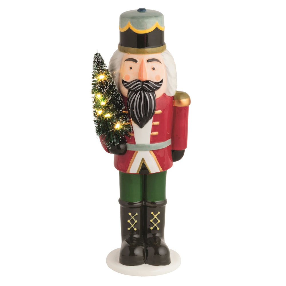 Hand-painted ceramic LED Nutcracker Sitter in a red uniform holding a lighted evergreen tree.