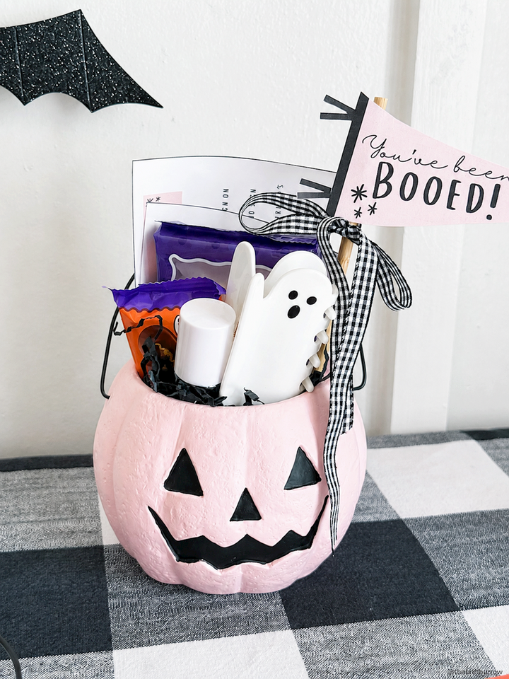 Mini Halloween Treat Bucket in light pink, hand-painted jack-o’-lantern design, comes filled with candy, a ghost-shaped treat, and a “You’ve been BOOED!” flag. Available in 3 styles.