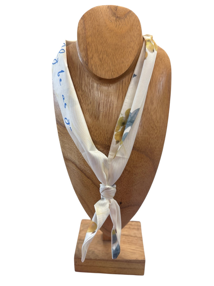 Cream silk scarf necklace with blue and yellow floral patterns, blue script text on edge. Available in S, M, L.