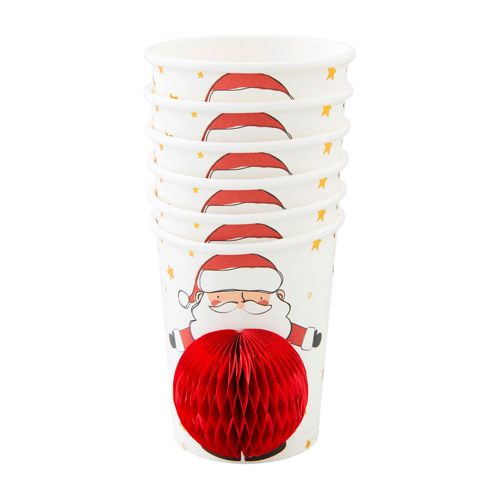 Stack of Santa Claus Christmas paper cups with a three-dimensional red honeycomb tissue paper ornament.