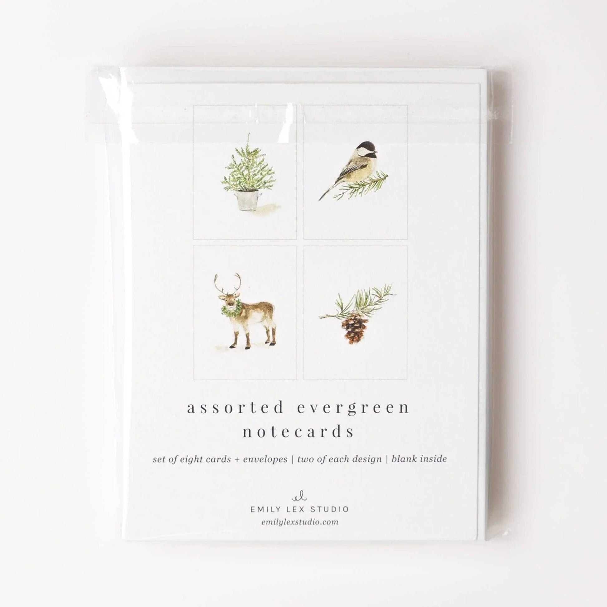 The Evergreen Christmas assorted notecard set includes eight blank notecards with envelopes, each featuring watercolor illustrations of a pine sprig, bird, reindeer, or pine tree. Sizes available: standard notecard.