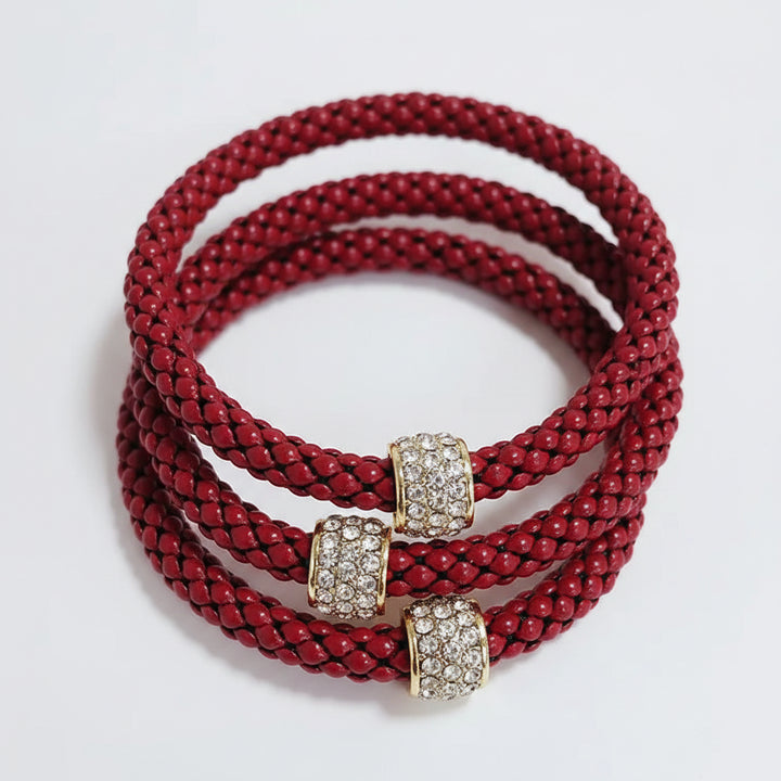 Three red braided bracelets with gold and diamond-encrusted clasps. Available sizes: small, medium, large.
