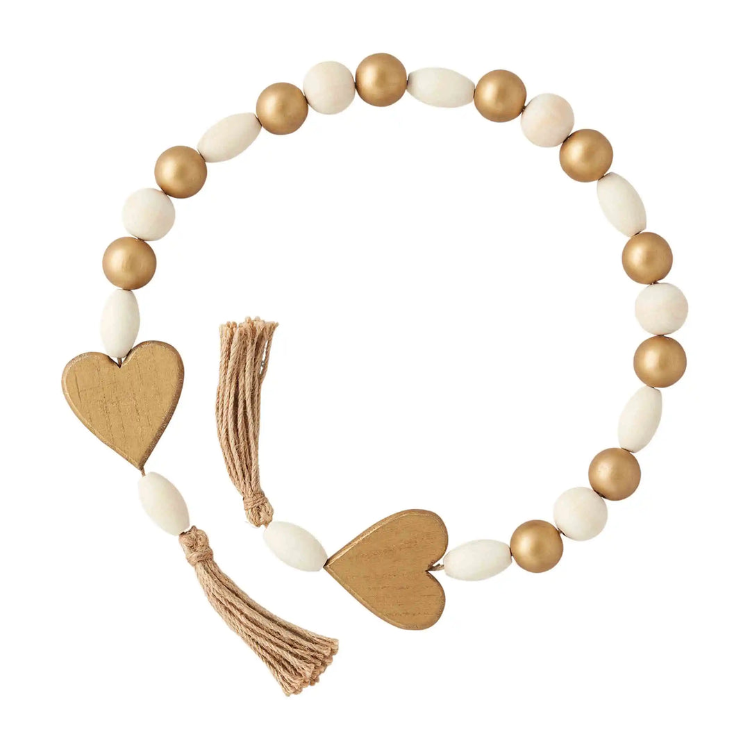 Gold and white bead garland with two gold heart accents, jute tassels at each end; available in 36” and 48” lengths.