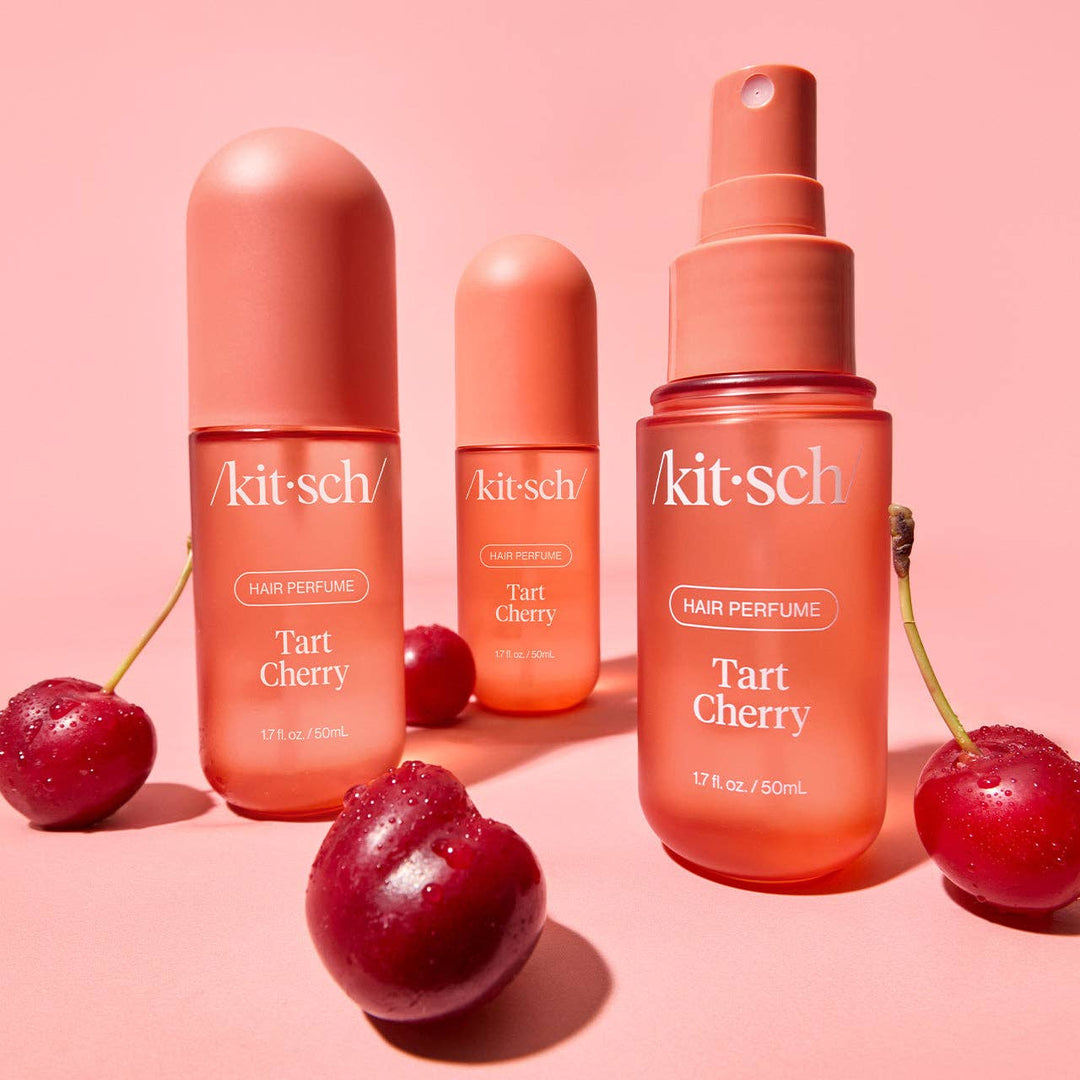 Three peachy-pink Tart Cherry Hair Perfume bottles with odor-eliminating tech, available in multiple sizes.