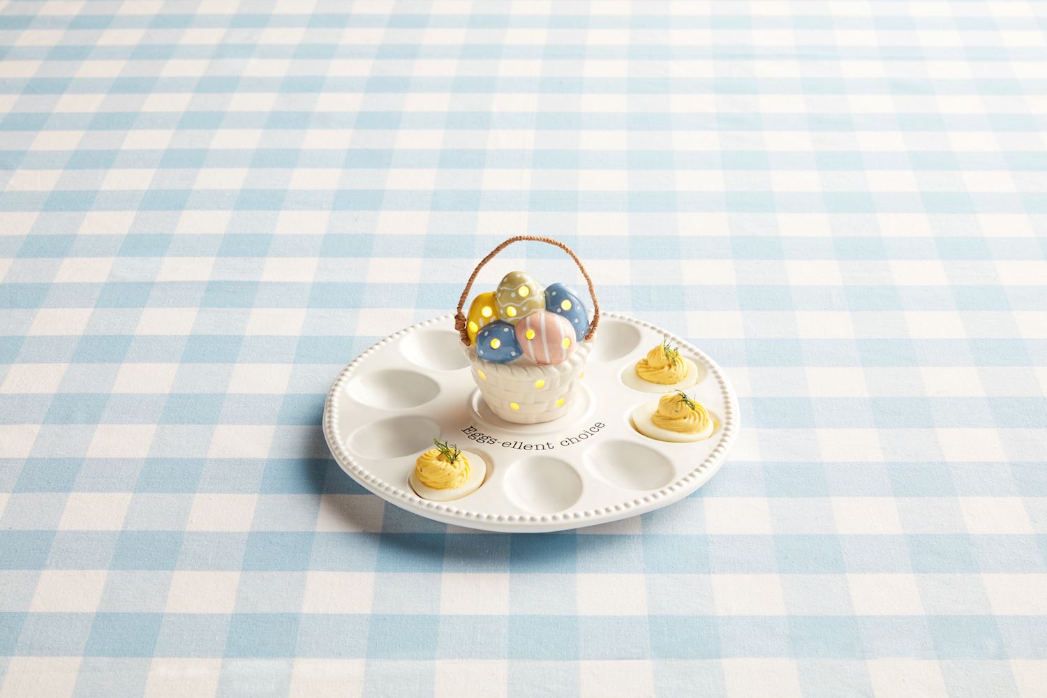 The Deviled Egg Tray Light-Up Holder features a ceramic design with space for four deviled eggs, complemented by a colorful egg holder shaped like an ornate basket. Available in one size.