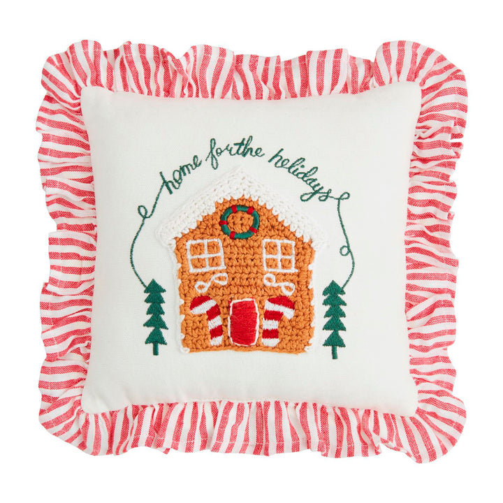Mini square Christmas crochet pillows featuring a gingerbread house, evergreen trees, “home for the holidays” embroidery, and a red and white striped French ticking ruffle.