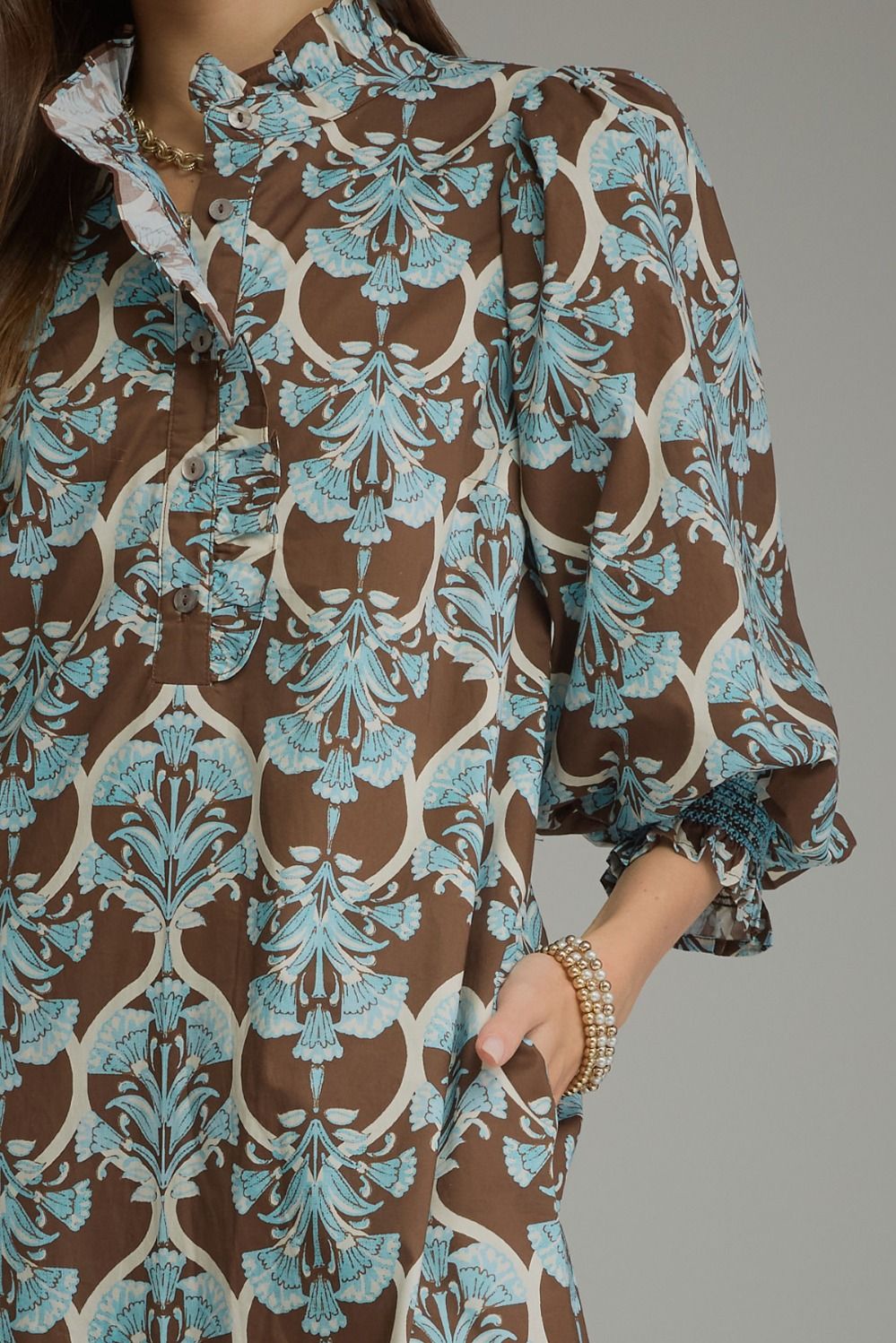 Lena Ruffle Midi Dress in a brown and light blue floral pattern with a ruffle collar, button-front, and puff sleeves with elasticated ruffled cuffs. Available in various sizes.