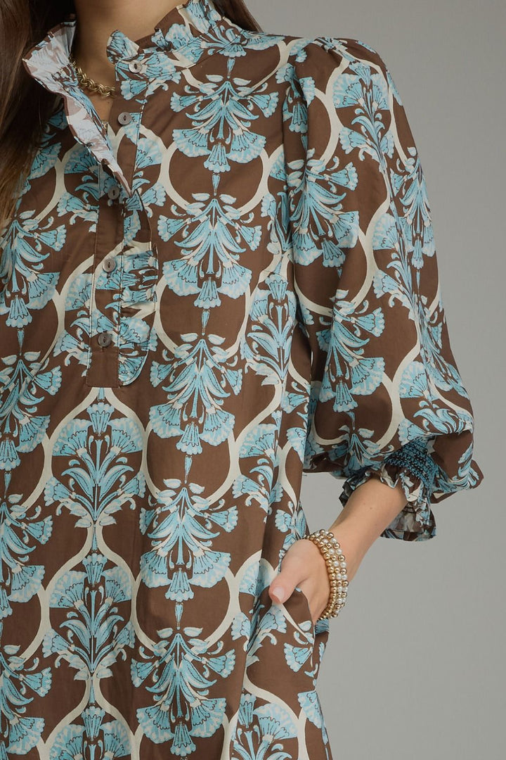 Lena Ruffle Midi Dress in a brown and light blue floral pattern with a ruffle collar, button-front, and puff sleeves with elasticated ruffled cuffs. Available in various sizes.