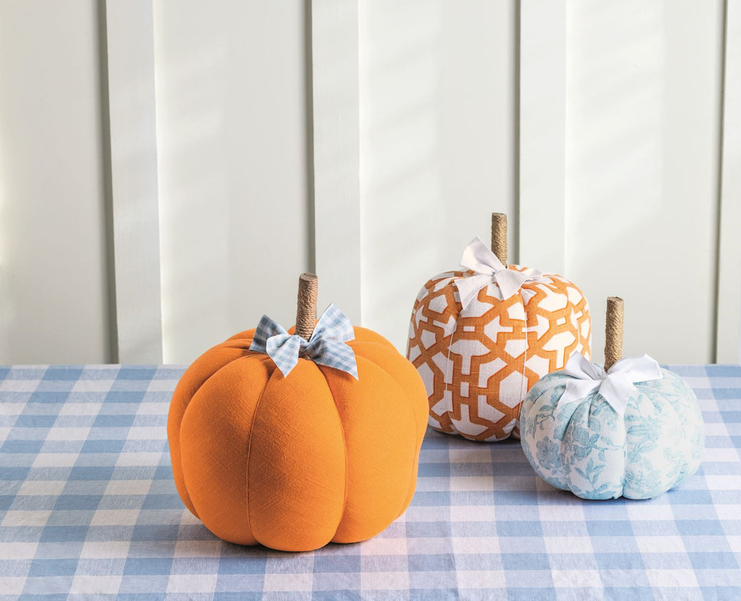 Set of three fabric pumpkins in orange, patterned orange-and-white, and blue patterned designs with bows; available in three sizes.