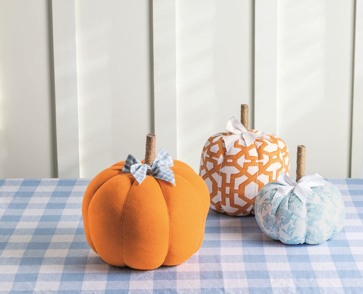 Set of three fabric pumpkins in orange, patterned orange-and-white, and blue patterned designs with bows; available in three sizes.