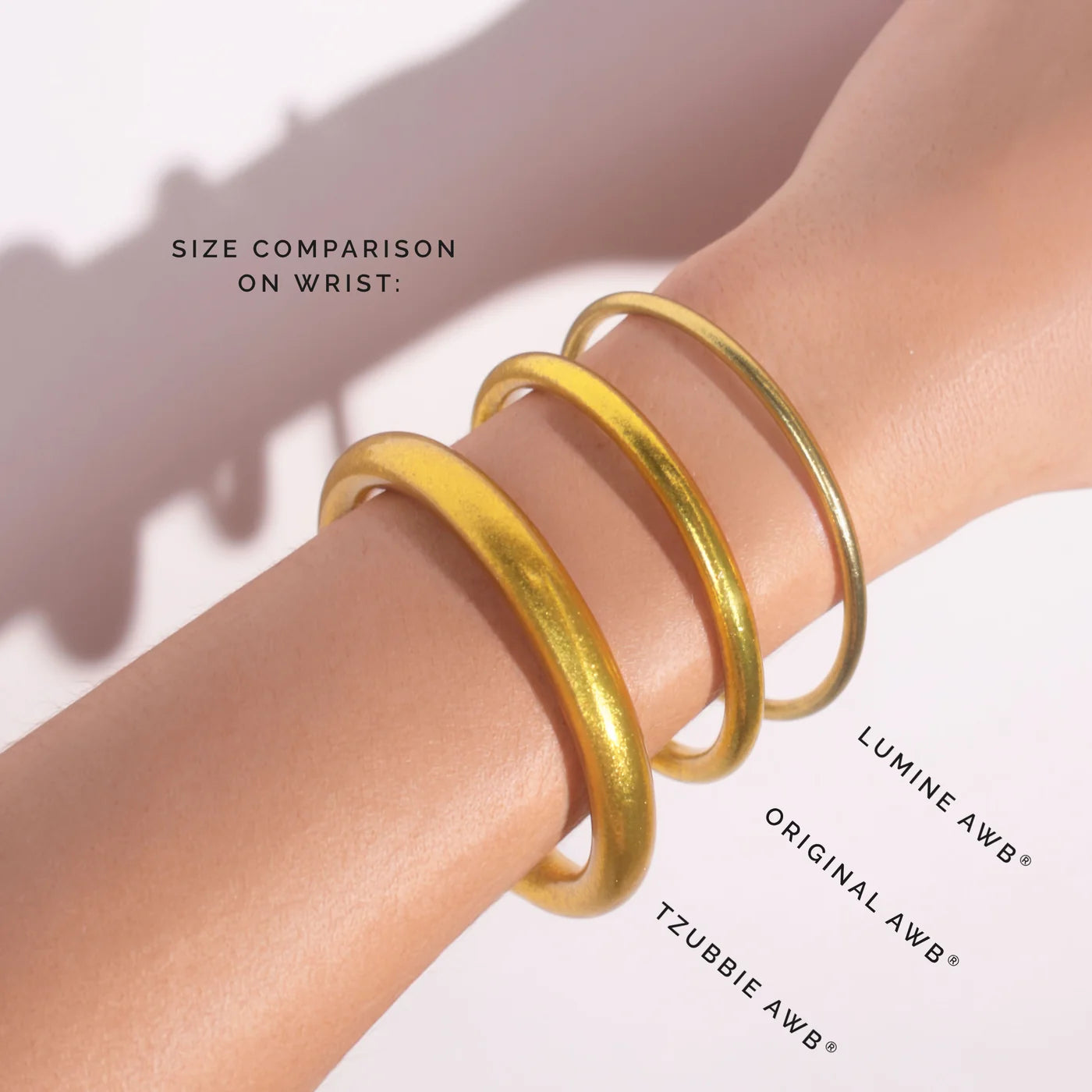 Three handcrafted gold Aura Lumine All Weather Bangles in large, each a different thickness. Available sizes: Large.