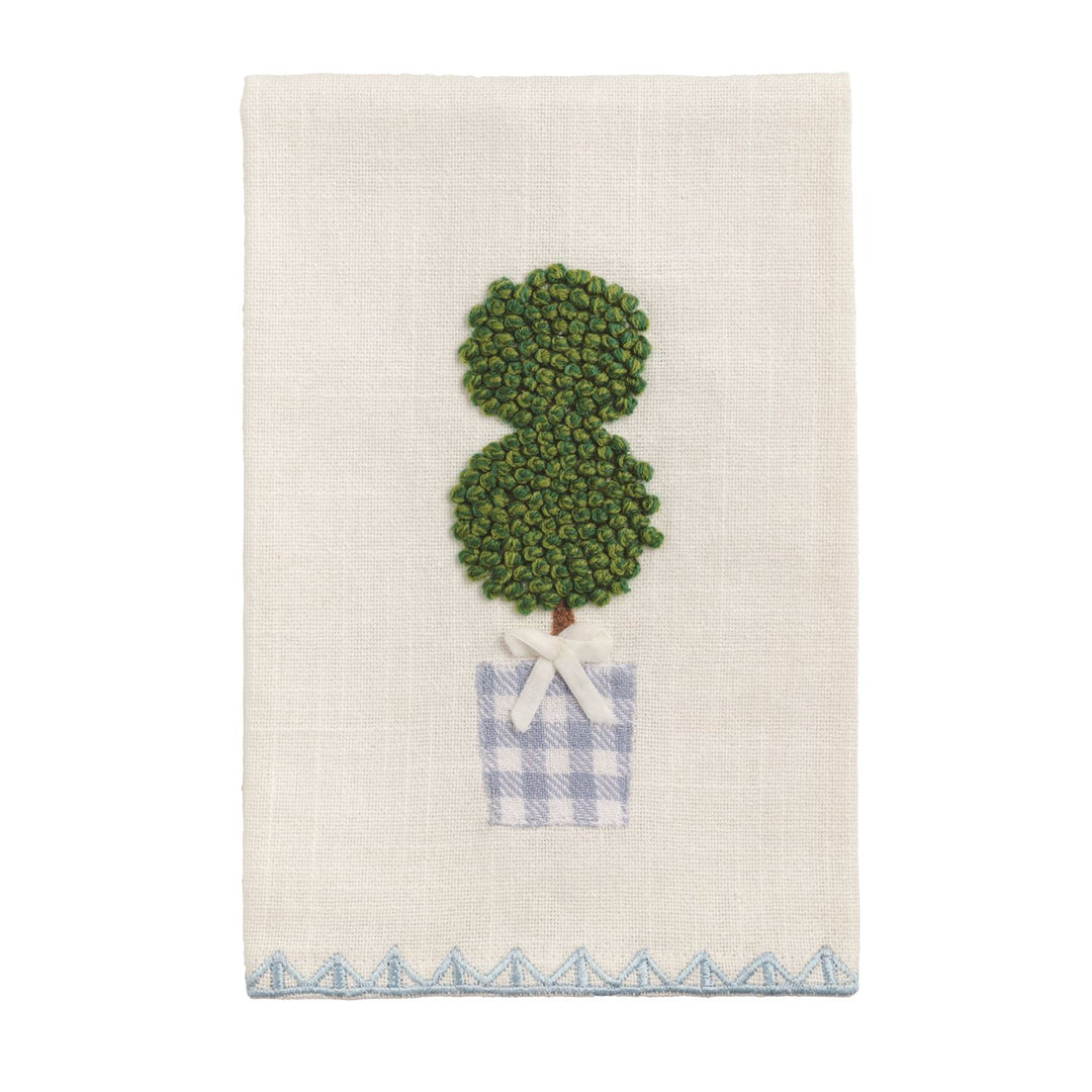 White cotton tea towel with embroidered topiary, blue-checkered pot, white bow, blue zigzag border. Size: 20" x 28".