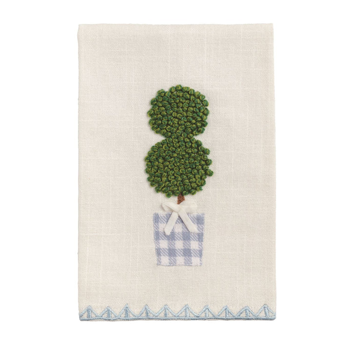 White cotton tea towel with embroidered topiary, blue-checkered pot, white bow, blue zigzag border. Size: 20" x 28".