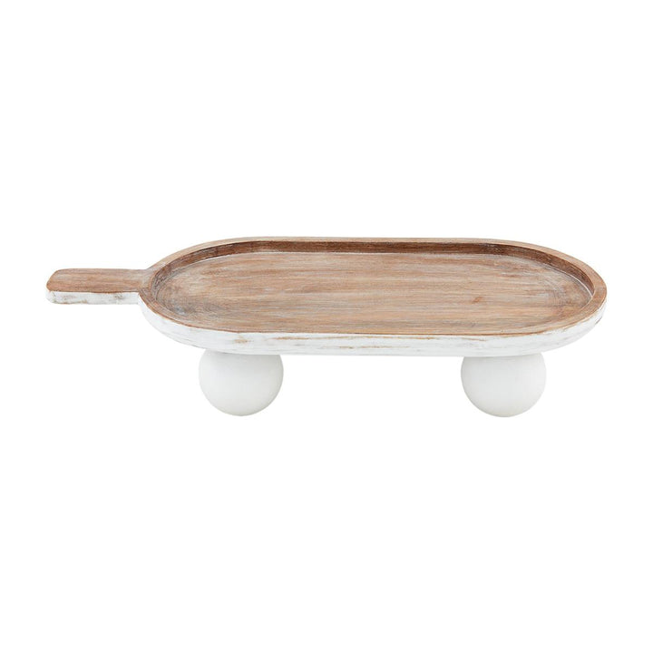 The Bead Footed Paddle Board is a mango wood serving tray with a handle and two round white legs, offering a rustic look. Available sizes: Small, Medium, Large.