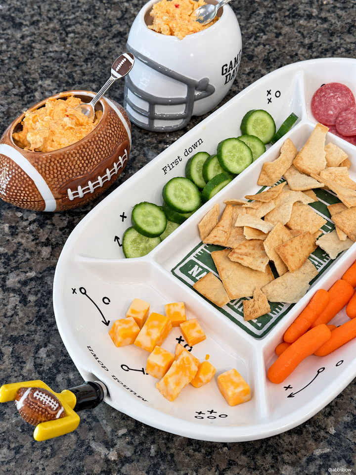 Game Day Dip Bowl set includes two football-shaped dip bowls, stocked with pita chips, cucumber slices, cheese cubes, carrots, and salami. Sizes available: small and large. Matching football bottle opener included.