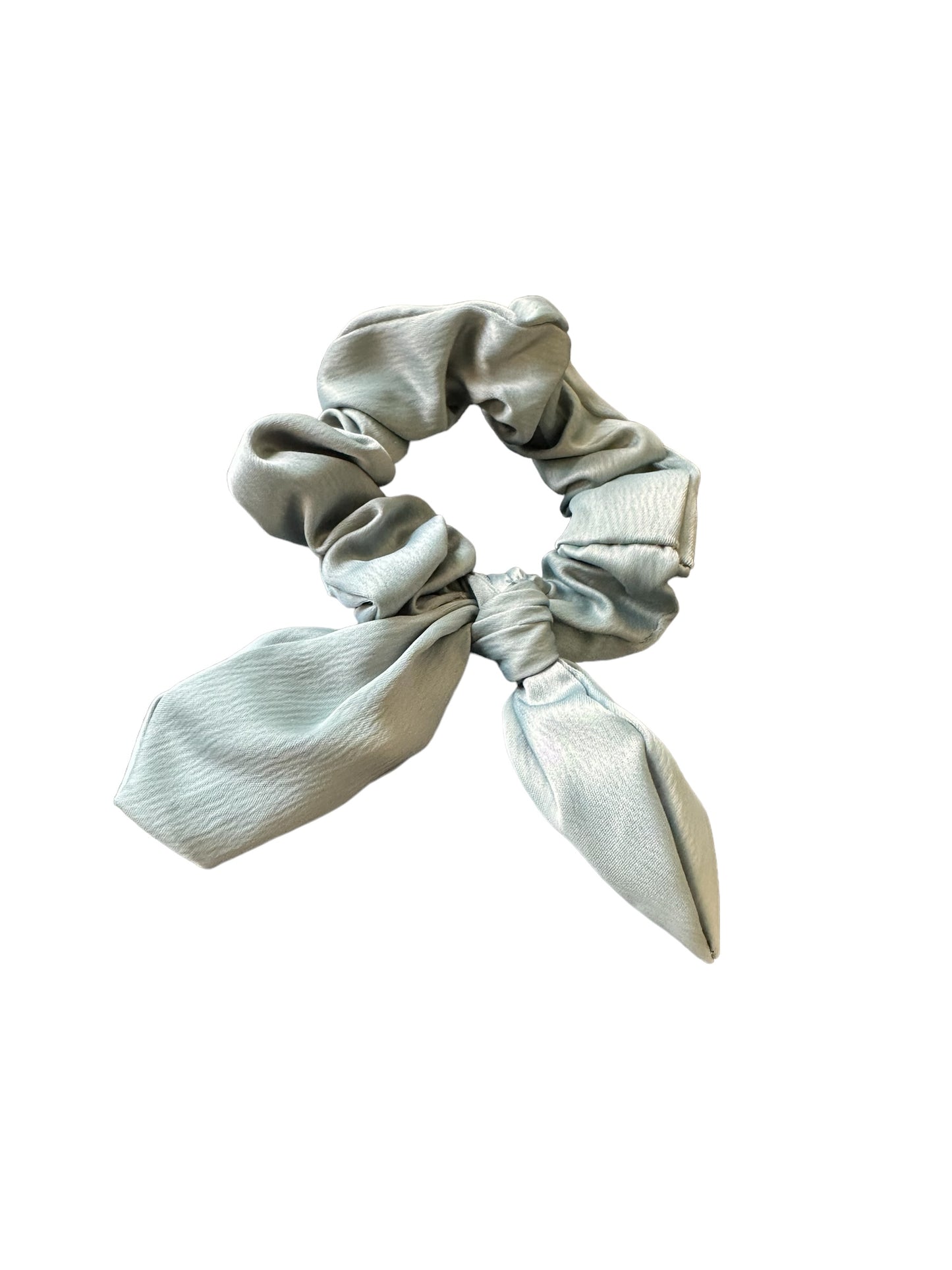 Light blue satin scrunchie with two tails resembling a bow design. Soft, shiny texture with a slightly wrinkled appearance. Available sizes: Small, Medium.