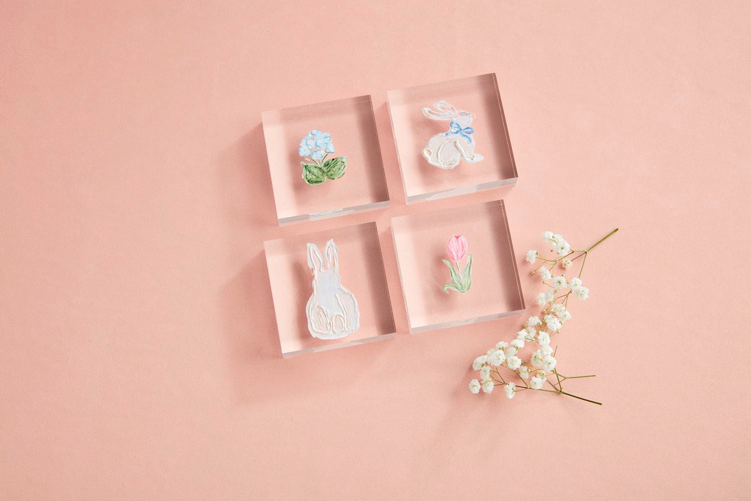 The Spring Acrylic Block set includes four clear blocks showcasing hand-painted acrylic art: a vibrant flower, a rabbit with a blue bow, another rabbit, and a tulip. Sizes available: Standard.