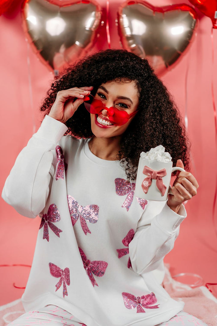 White sweatshirt with pink glitter bows, available in S-XL.