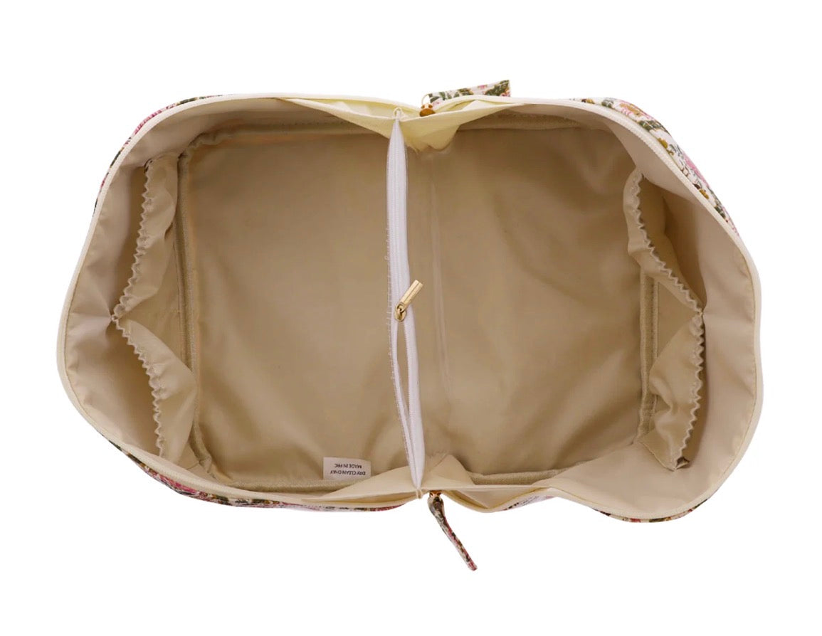 The Travel Organizer | Large has an open floral pattern, beige interior, central zippered pocket, and elastic side pockets. Available in large size.