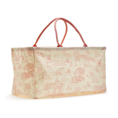 The Animal Toile Hamper/Storage Tote is a rectangular bag with pink handles. Light cream background with pink illustrated toile pattern featuring pastoral scenes. Made from durable cotton canvas with matching pink outlined edges. Available in one size.