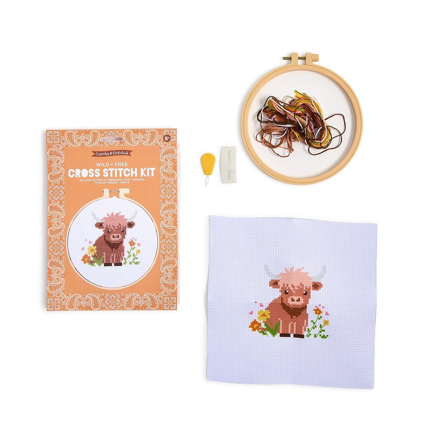 Wild & Free Cross Stitch Kit: orange box, hoop with threads, needle threader, needles, finished cow piece. Sizes not specified.