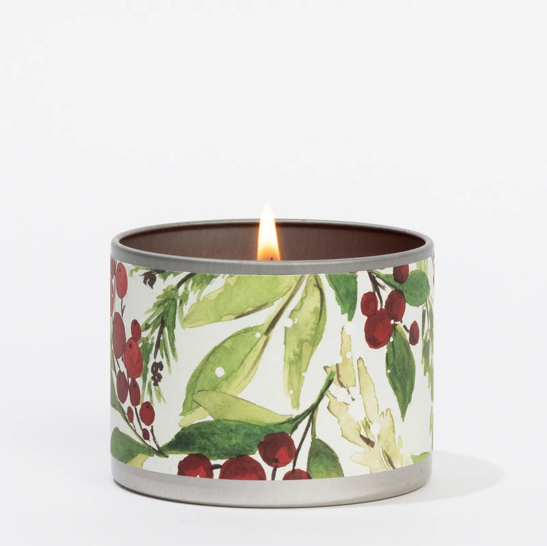 Lit 4oz Merry Memories tin candle with holly and evergreen watercolor print.