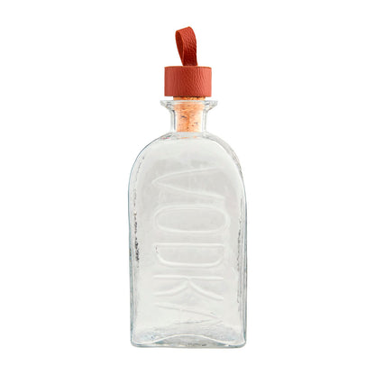 The Embossed Glass Decanter is a clear glass bottle with "VODKA" elegantly embossed on the front. Crafted from high-quality glass, it has a rectangular shape with rounded edges and a cork stopper adorned with a brown leather strap. Available in one size: 750ml.