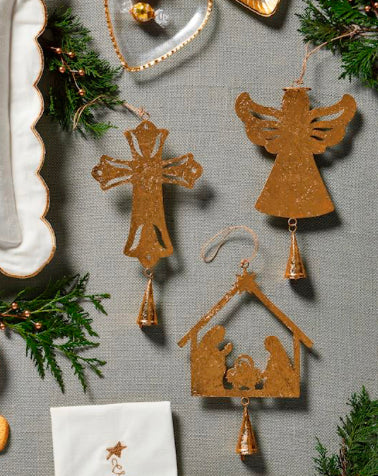 Three gold-colored, filigree foiled tin ornaments in cross, angel, and nativity shapes with hanging bells.