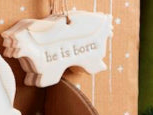 Stoneware manger ornament embossed with “he is born.”.