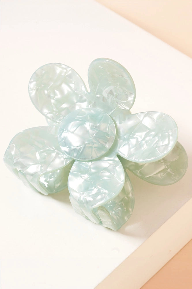 The Daisy Pearlized Hair Clip is a translucent light green flower-shaped hair accessory with large, rounded petals and a textured surface. Available in one size.