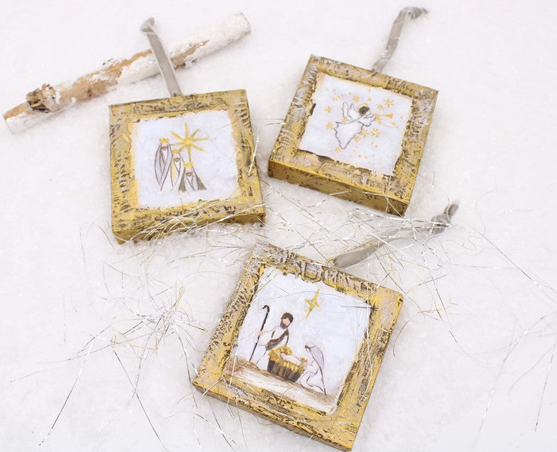 Three square hand-painted canvas Nativity ornaments with gold frames and hanging ribbons.