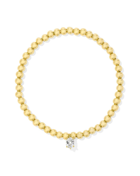 Gold beaded stretch bracelet with a single round white crystal charm at the center. Available in one size.