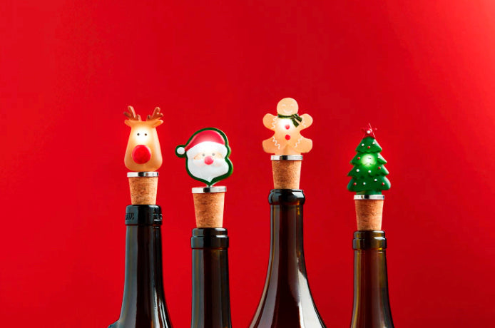 Four Christmas light-up bottle stoppers: reindeer, Santa, gingerbread man, and Christmas tree.