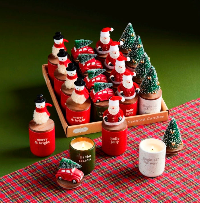 Scented soy wax Christmas candles with wooden lids, topped with miniature snowmen, Santas, red cars with trees, and bottle brush trees.