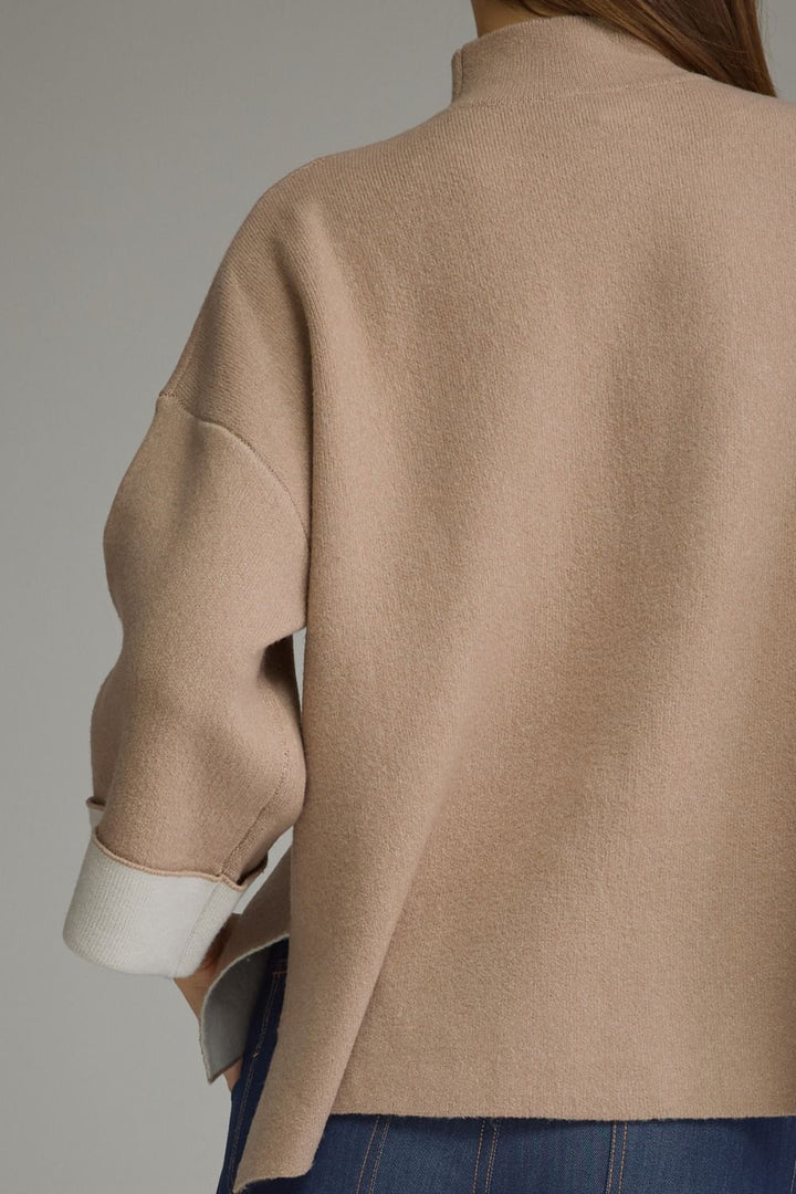 Tan mock neck sweater with solid knit, dropped shoulders, and contrasting white three-quarter sleeves. Available in sizes.