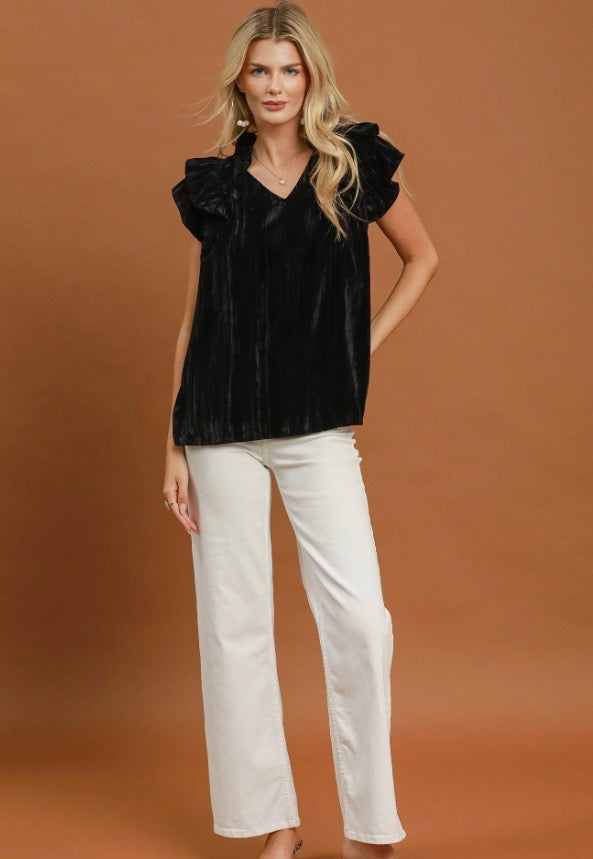 The Velvet Ruffle Blouse in black features delicate ruffle detailing and is available in sizes XS–XL.