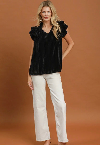 The Velvet Ruffle Blouse in black features delicate ruffle detailing and is available in sizes XS–XL.