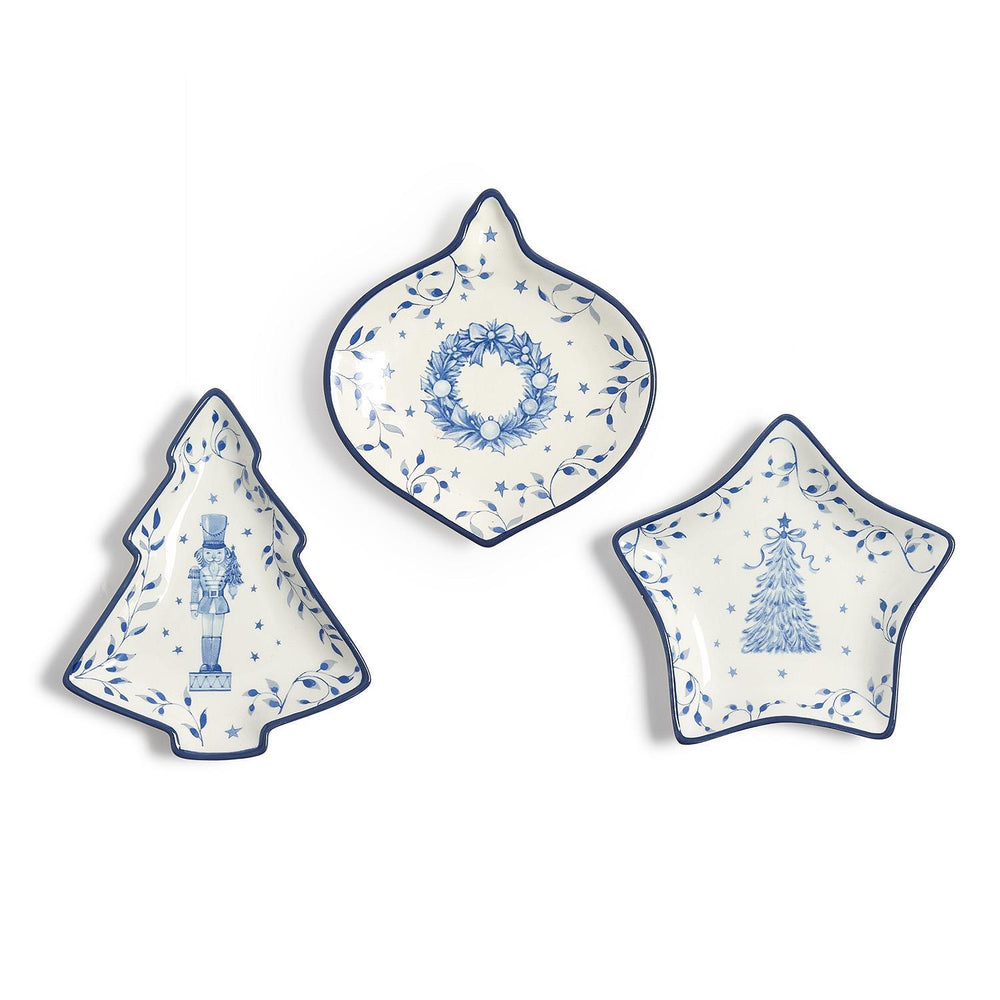 Season’s Gala Tidbit Dishes in three blue-and-white shapes: a nutcracker-adorned tree, a wreath-patterned ornament, and a pine-tree star.