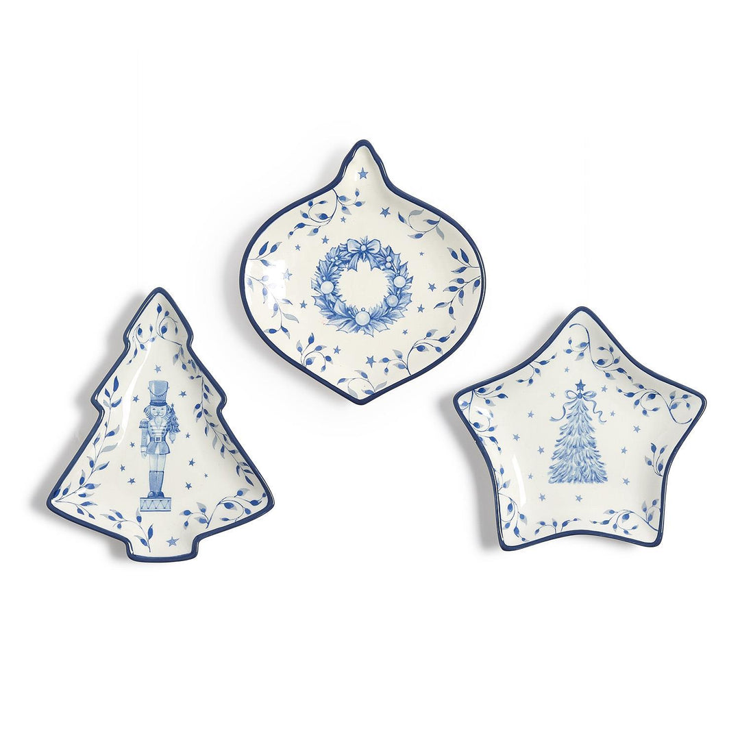 Season’s Gala Tidbit Dishes in three blue-and-white shapes: a nutcracker-adorned tree, a wreath-patterned ornament, and a pine-tree star.