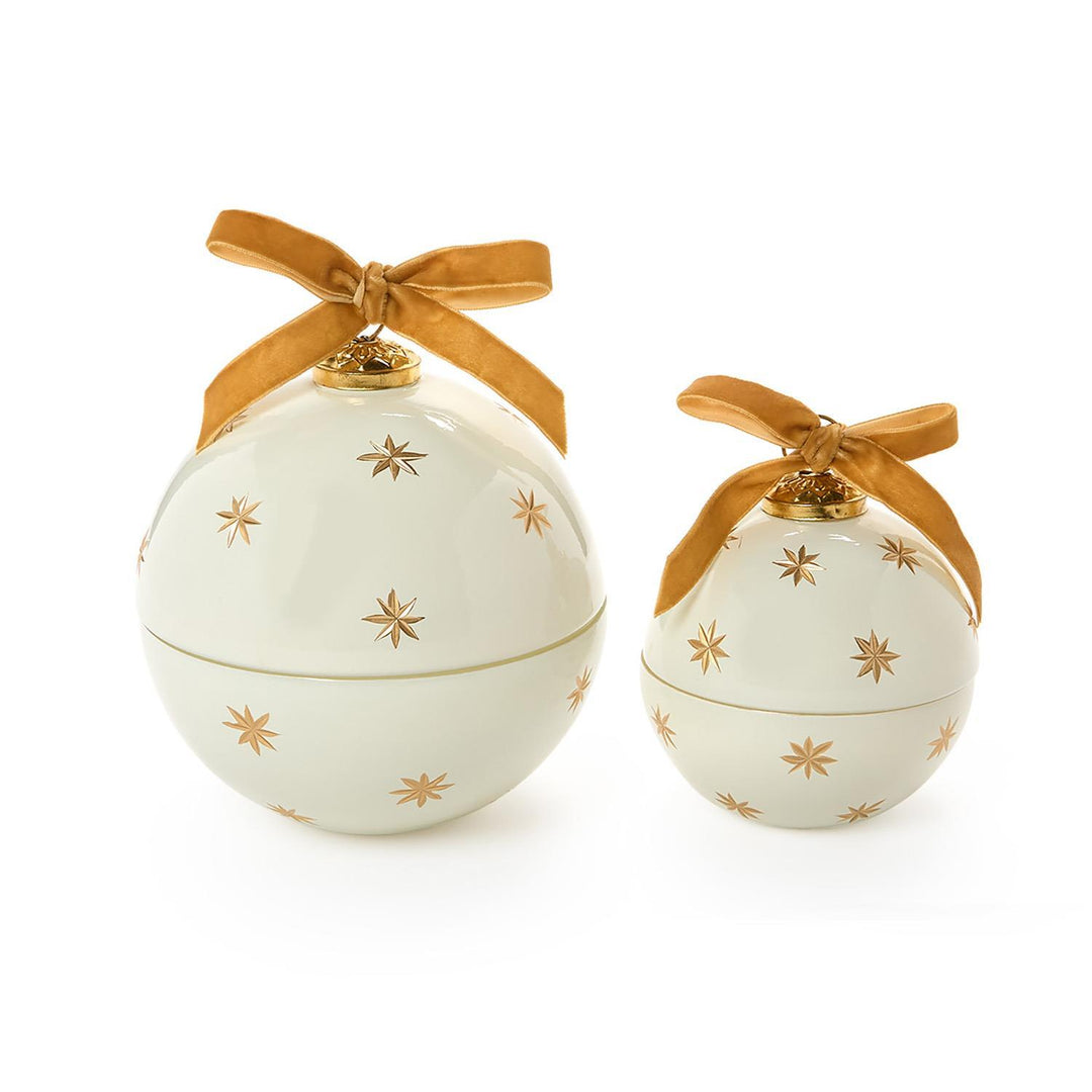 Two Sparkling Rose Ornament Candles in two sizes, featuring cream-colored round designs with gold star patterns and gold ribbon bows.