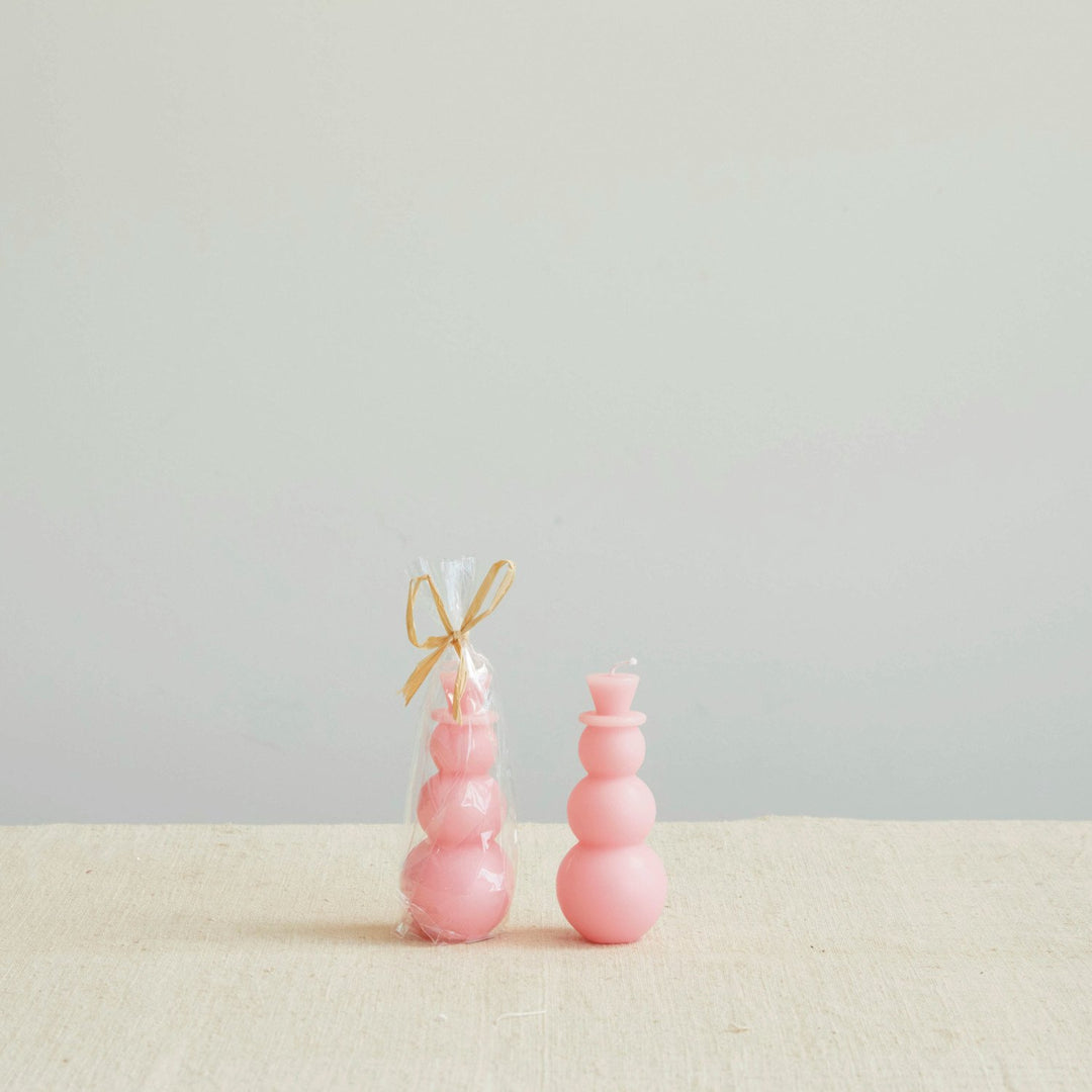 Two pink snowman-shaped candles.