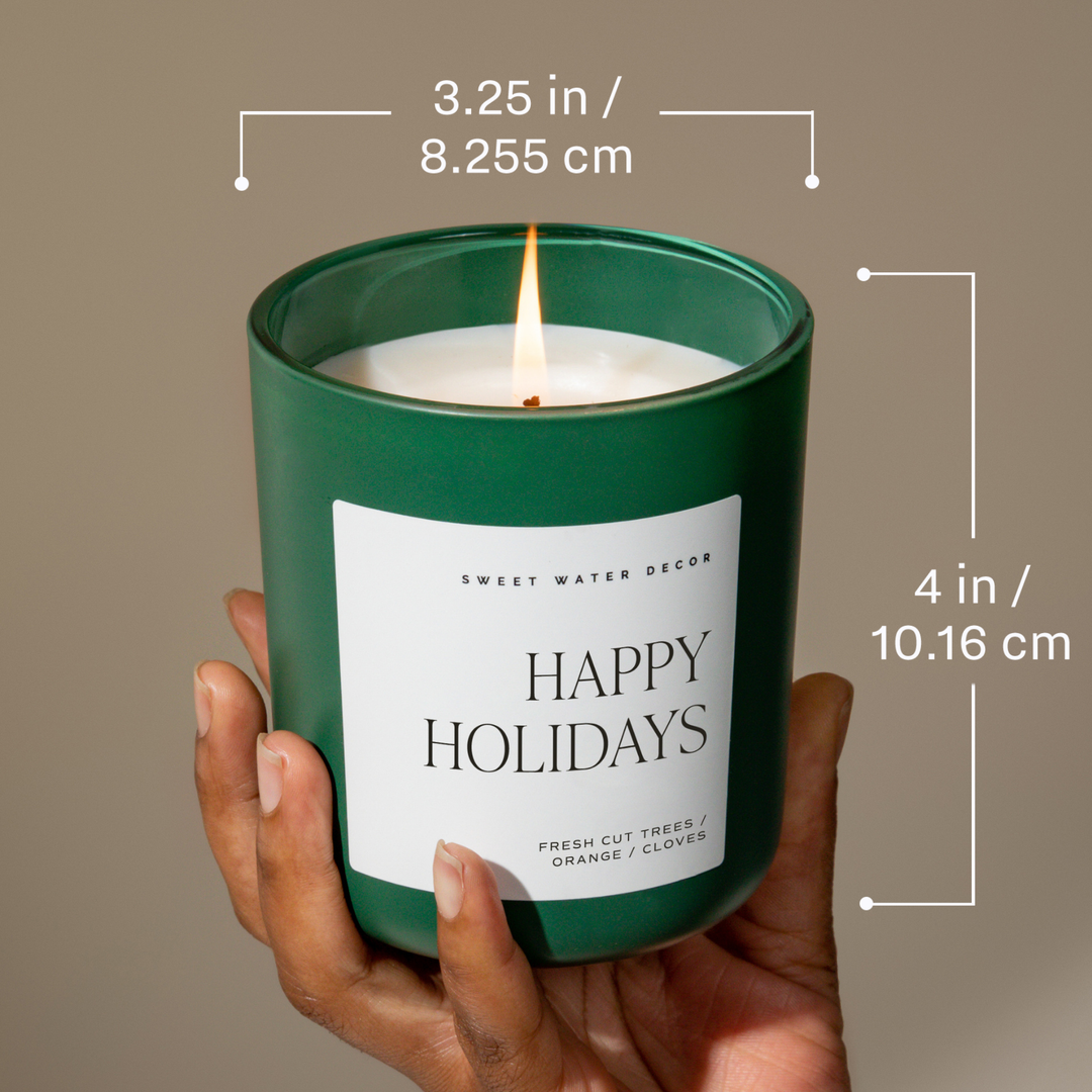 15 oz Under the Mistletoe soy matte candle in a green “Happy Holidays” jar with a lit wick, 3.25 inches wide and 4 inches tall.